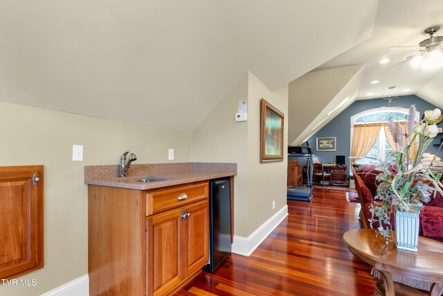 bar featuring dark wood-type flooring, ceiling fan, sink, and vaulted ceiling