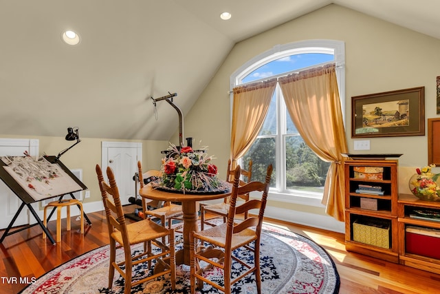 dining space with vaulted ceiling and wood-type flooring