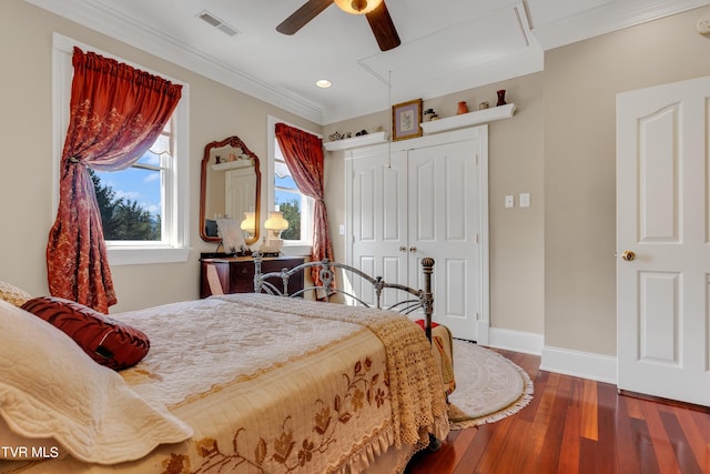 bedroom with crown molding, dark wood-type flooring, ceiling fan, and a closet