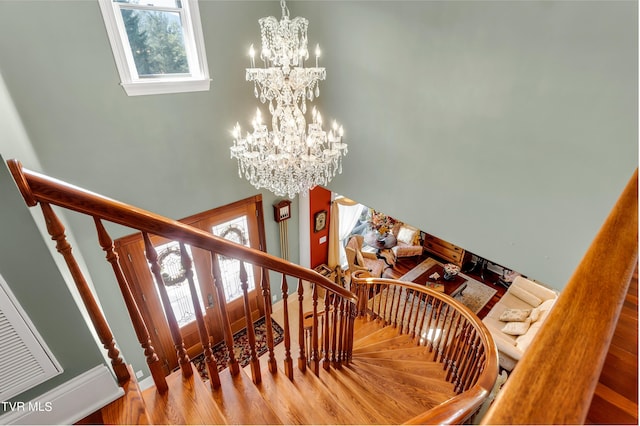 stairs featuring hardwood / wood-style floors and a notable chandelier