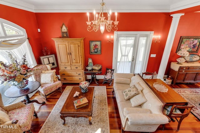 living room with hardwood / wood-style flooring, ornamental molding, a chandelier, and decorative columns