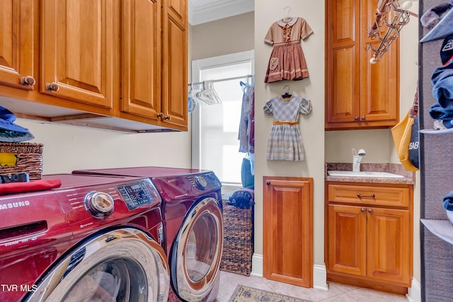 clothes washing area with cabinets, crown molding, light tile patterned floors, washing machine and clothes dryer, and sink