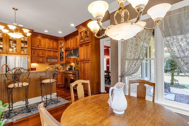 dining space with dark hardwood / wood-style flooring, an inviting chandelier, and ornamental molding