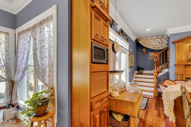 kitchen with crown molding, hardwood / wood-style floors, and stainless steel microwave