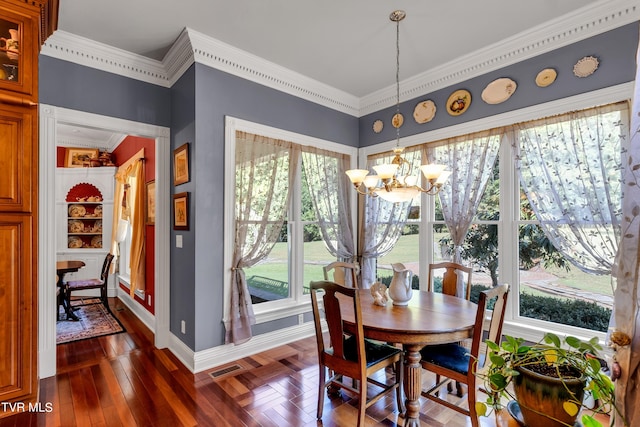 dining area with dark wood-type flooring, a chandelier, and ornamental molding