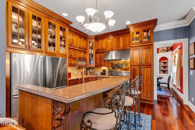 kitchen featuring stainless steel refrigerator, ornamental molding, a chandelier, decorative light fixtures, and dark wood-type flooring