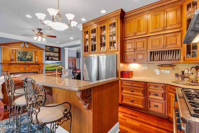 kitchen with dark hardwood / wood-style floors, decorative light fixtures, ceiling fan with notable chandelier, stainless steel appliances, and ornamental molding