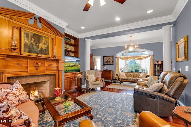 living room featuring ceiling fan with notable chandelier, decorative columns, hardwood / wood-style flooring, and ornamental molding