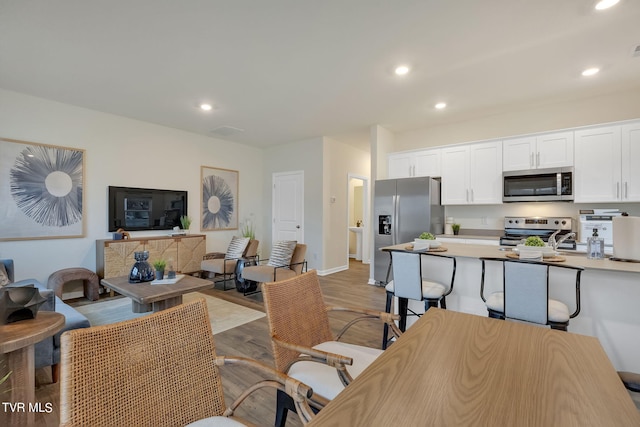 interior space featuring appliances with stainless steel finishes, recessed lighting, white cabinetry, and light wood finished floors