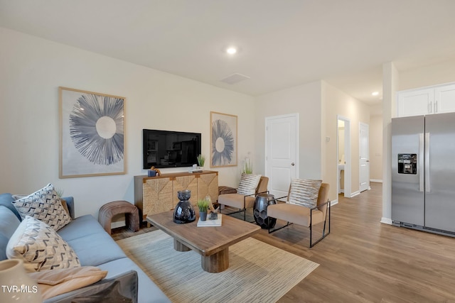 living area with light wood-style floors, baseboards, and recessed lighting