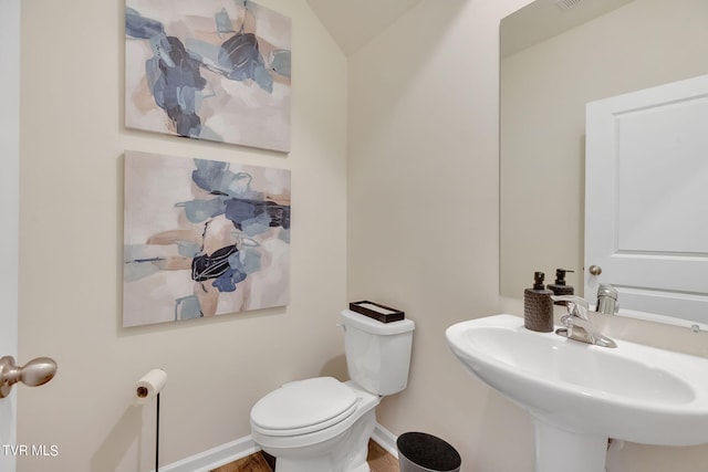 half bathroom with visible vents, a sink, toilet, and baseboards