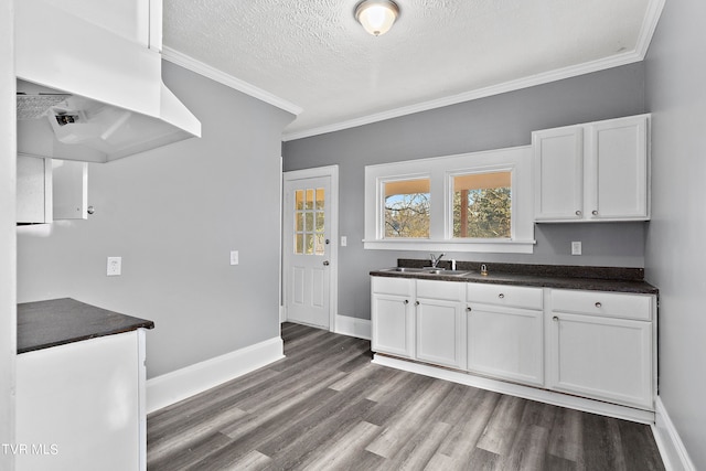 kitchen featuring crown molding, a textured ceiling, sink, dark wood-type flooring, and white cabinets