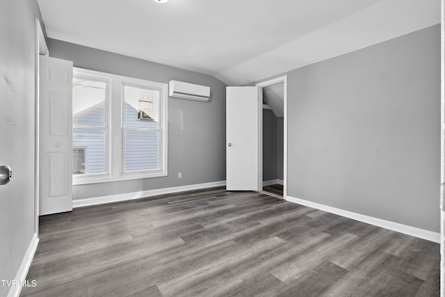 unfurnished room featuring lofted ceiling, a wall mounted AC, and dark wood-type flooring