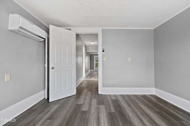 empty room featuring a wall mounted AC, dark hardwood / wood-style flooring, ornamental molding, and a textured ceiling