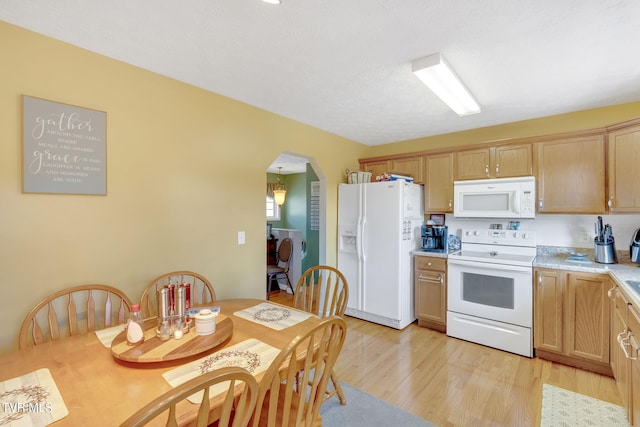 kitchen with a textured ceiling, white appliances, and light hardwood / wood-style floors