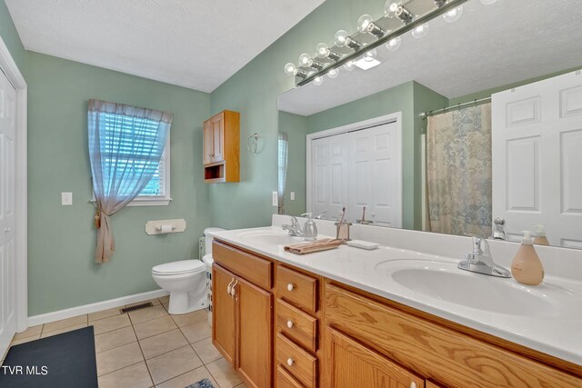 bathroom with vanity, toilet, a textured ceiling, and tile patterned flooring