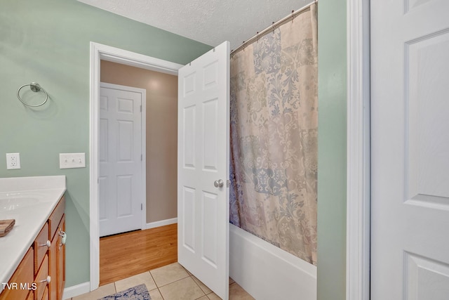 bathroom with tile patterned floors, shower / bath combo, a textured ceiling, and vanity