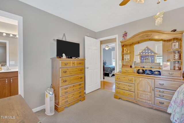 bedroom featuring multiple windows, ceiling fan, light carpet, and ensuite bath