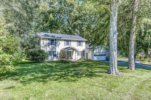 colonial house with a garage, a front yard, and driveway