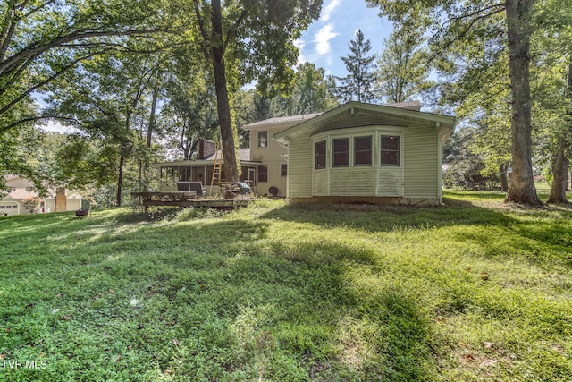 rear view of house featuring a wooden deck, a lawn, and a chimney