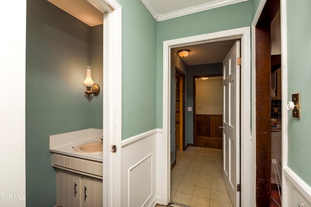 corridor featuring wood walls, light tile patterned floors, ornamental molding, and sink