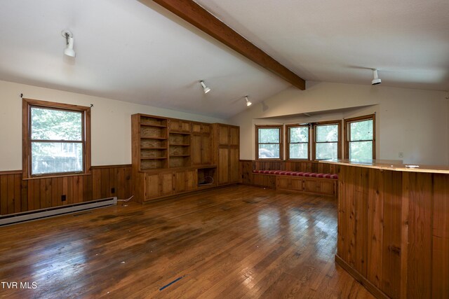 unfurnished living room with plenty of natural light, wood walls, vaulted ceiling with beams, and dark hardwood / wood-style floors