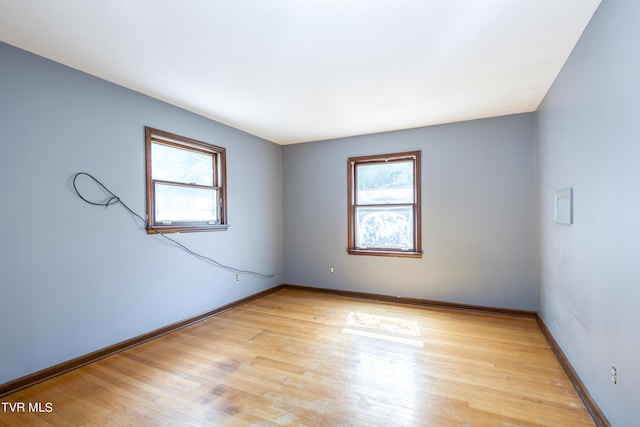 spare room featuring baseboards, a healthy amount of sunlight, and light wood-style flooring