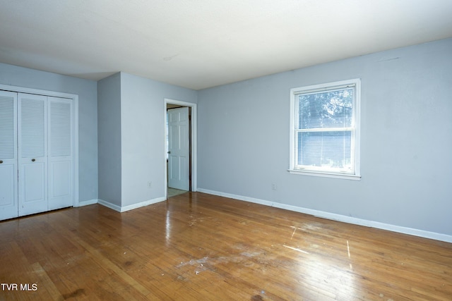 unfurnished bedroom featuring a closet, baseboards, and hardwood / wood-style flooring