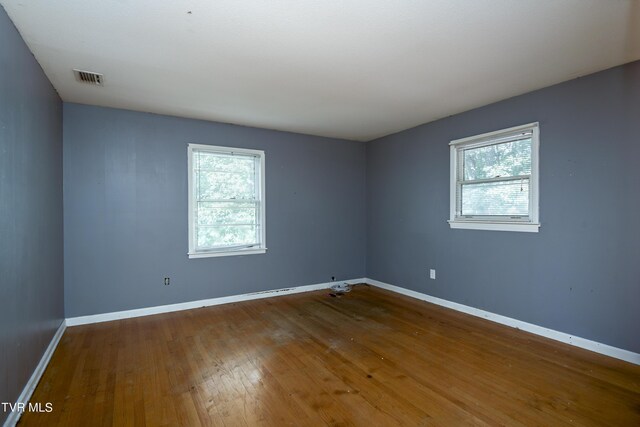 unfurnished room with a healthy amount of sunlight and hardwood / wood-style floors