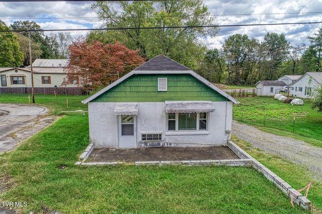 rear view of property with a lawn, fence, and stucco siding