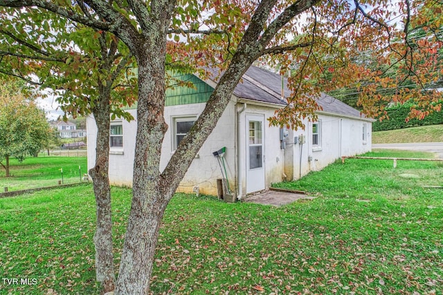 view of front facade with a shingled roof, a front lawn, and stucco siding