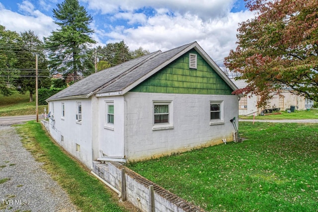 view of side of home with a lawn and a shingled roof