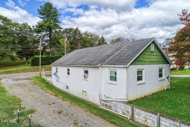 view of side of property with a yard and roof with shingles