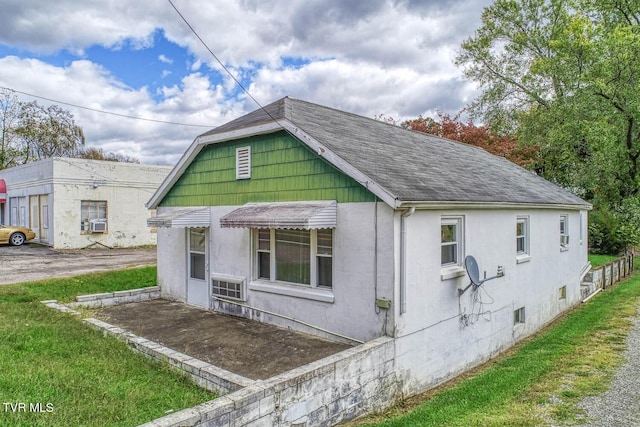 view of front of property with roof with shingles, stucco siding, and a front lawn