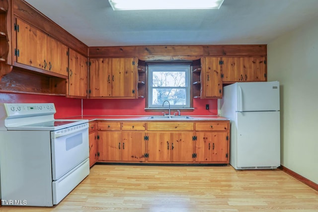 kitchen with brown cabinetry, a sink, light wood finished floors, and white appliances