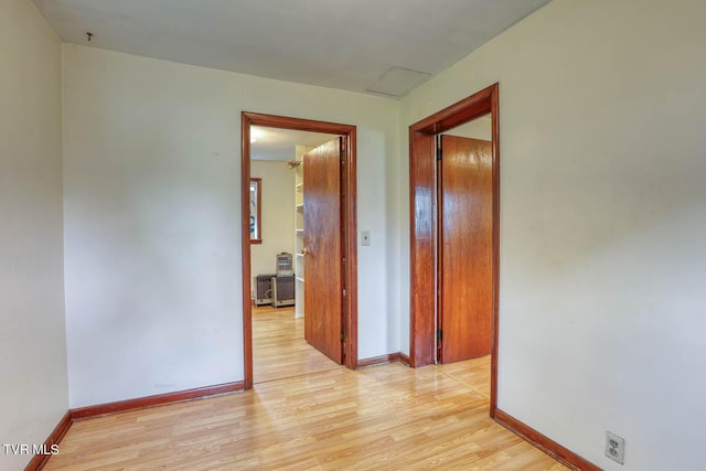 hallway with light wood-type flooring and baseboards
