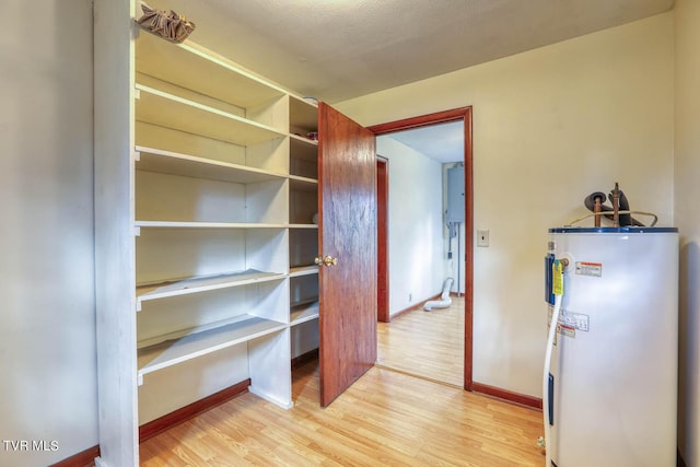 interior space featuring baseboards, water heater, and wood finished floors