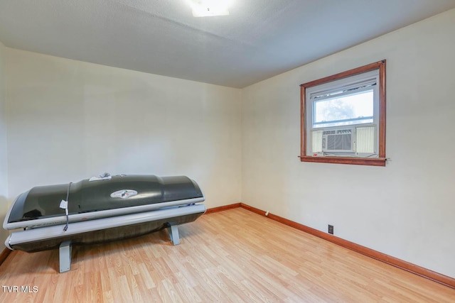 misc room with baseboards, cooling unit, and wood finished floors