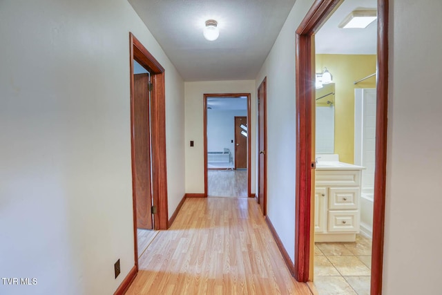 hall featuring baseboards and light wood finished floors