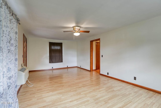 unfurnished room featuring a ceiling fan, baseboards, a wall unit AC, and light wood-style floors