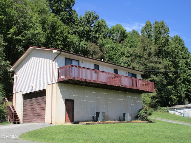 view of front of house with a front yard, cooling unit, a deck, and a garage