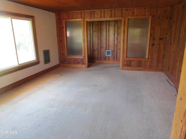 interior space featuring wood ceiling, wood walls, and light carpet