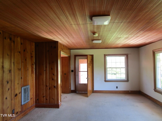 carpeted spare room featuring wooden ceiling and wood walls