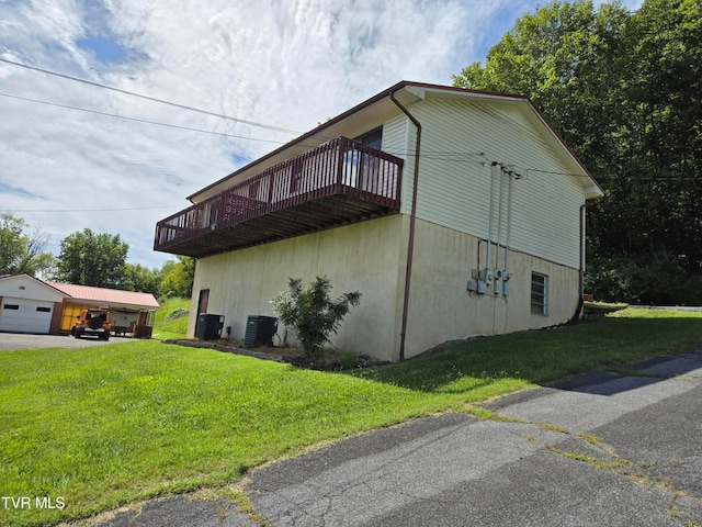 view of side of home with cooling unit, a deck, a lawn, an outbuilding, and a garage