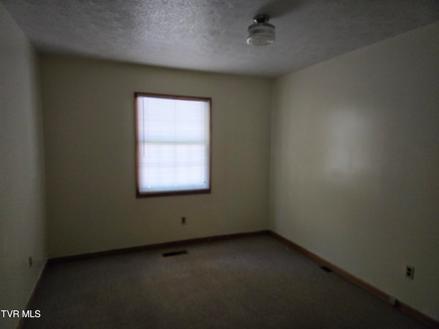 empty room with a textured ceiling and carpet