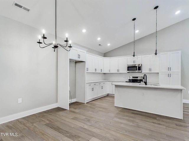 kitchen with a kitchen island with sink, white cabinets, hanging light fixtures, and appliances with stainless steel finishes