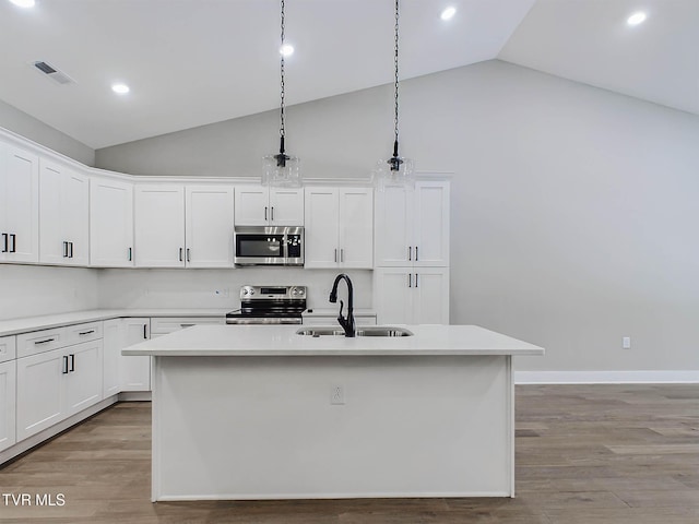 kitchen featuring stainless steel appliances, hanging light fixtures, a center island with sink, and sink