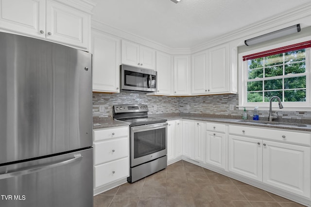 kitchen with light stone countertops, backsplash, stainless steel appliances, sink, and white cabinets