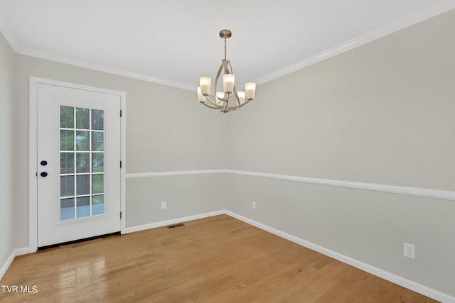 empty room featuring an inviting chandelier, crown molding, and light hardwood / wood-style flooring