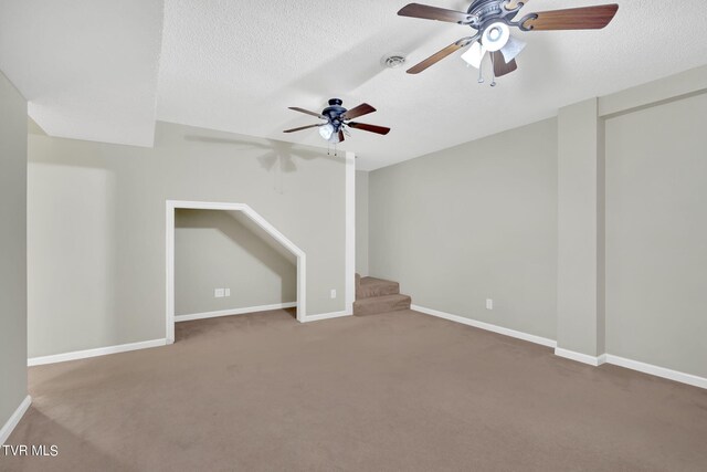 carpeted empty room with ceiling fan and a textured ceiling